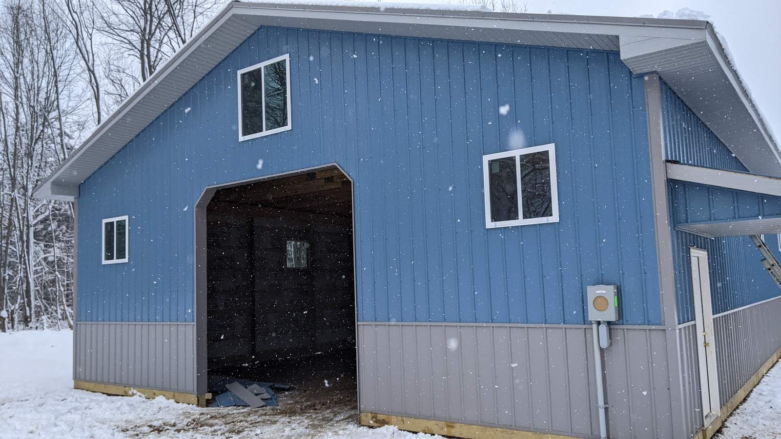 Blue and gray pole barn built during a Michigan winter