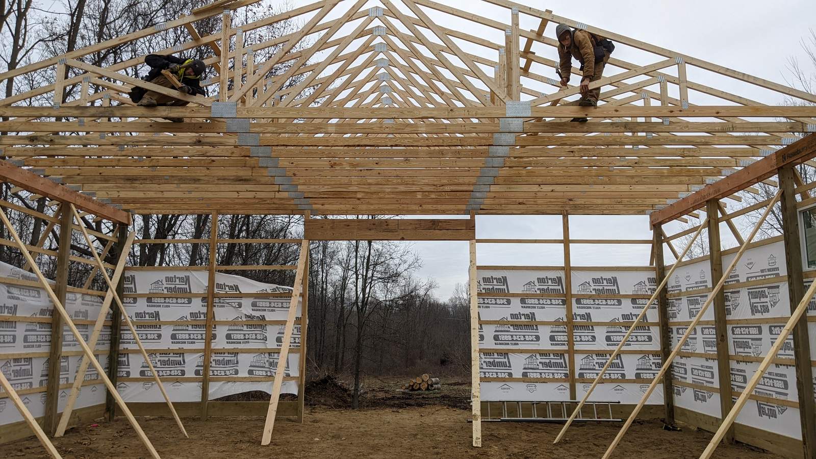 CNO crew setting roof trusses on a pole barn frame
