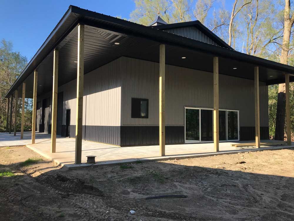 Black and tan post-frame shop building with wrap-around porch, built by CNO